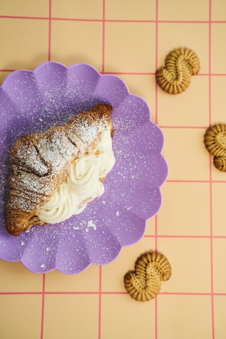 Täytetty croissant, jossa K. Leivon Leipomon kaneliässistä tehtyä kaneliässätahnaa ja jäätelöä, esillä pastellisessa kattauksessa.